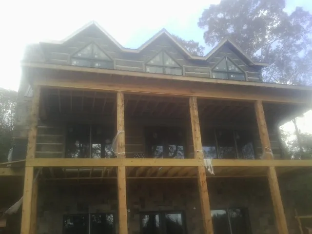 Dormers and porch framing on a large log home under construction — Roof Coating work by our crew in Northwood