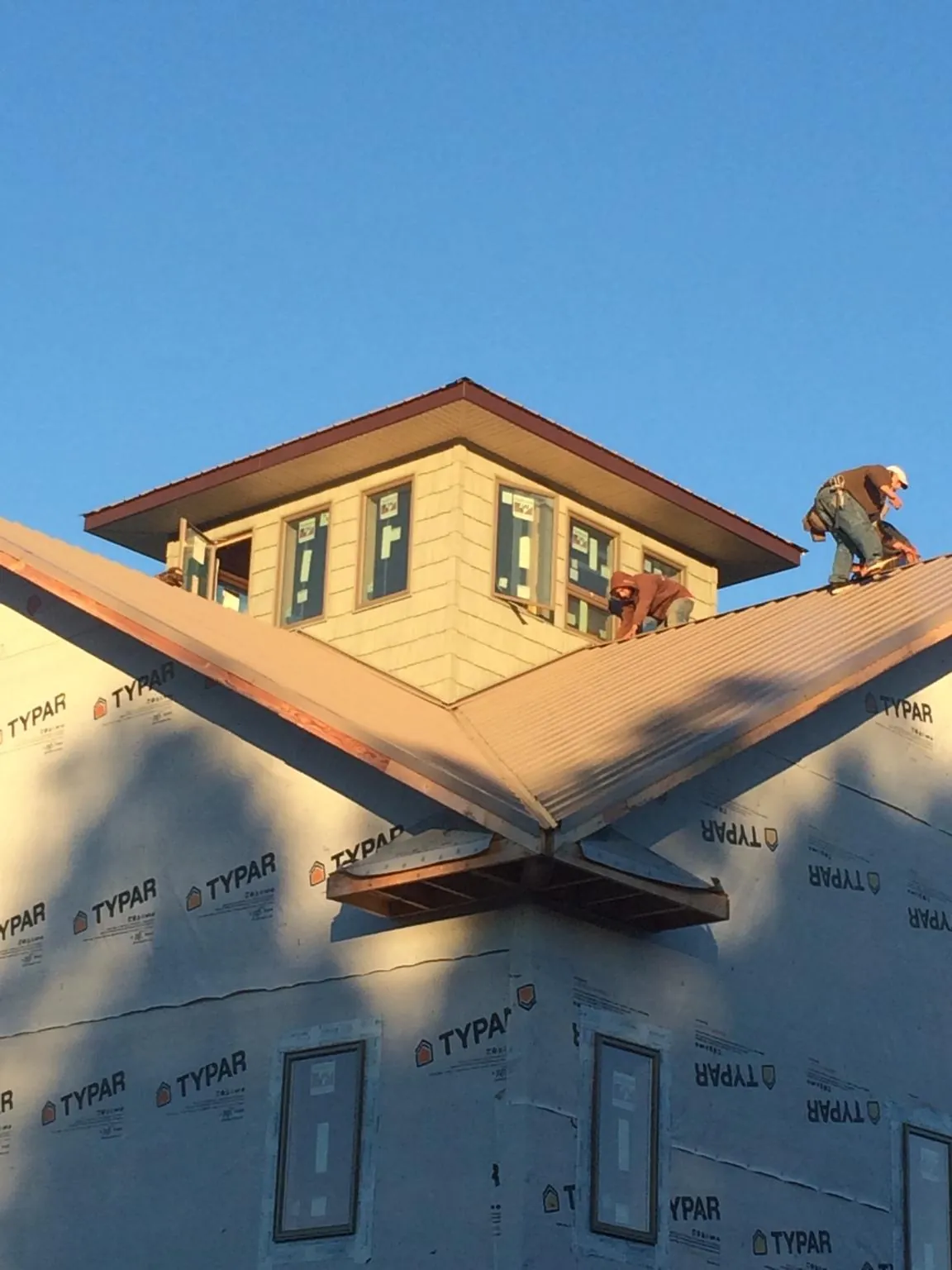Roofers working around a rooftop cupola on a new metal roof at sunset — Roof Waterproofing in Northwood by Roofing Brothers